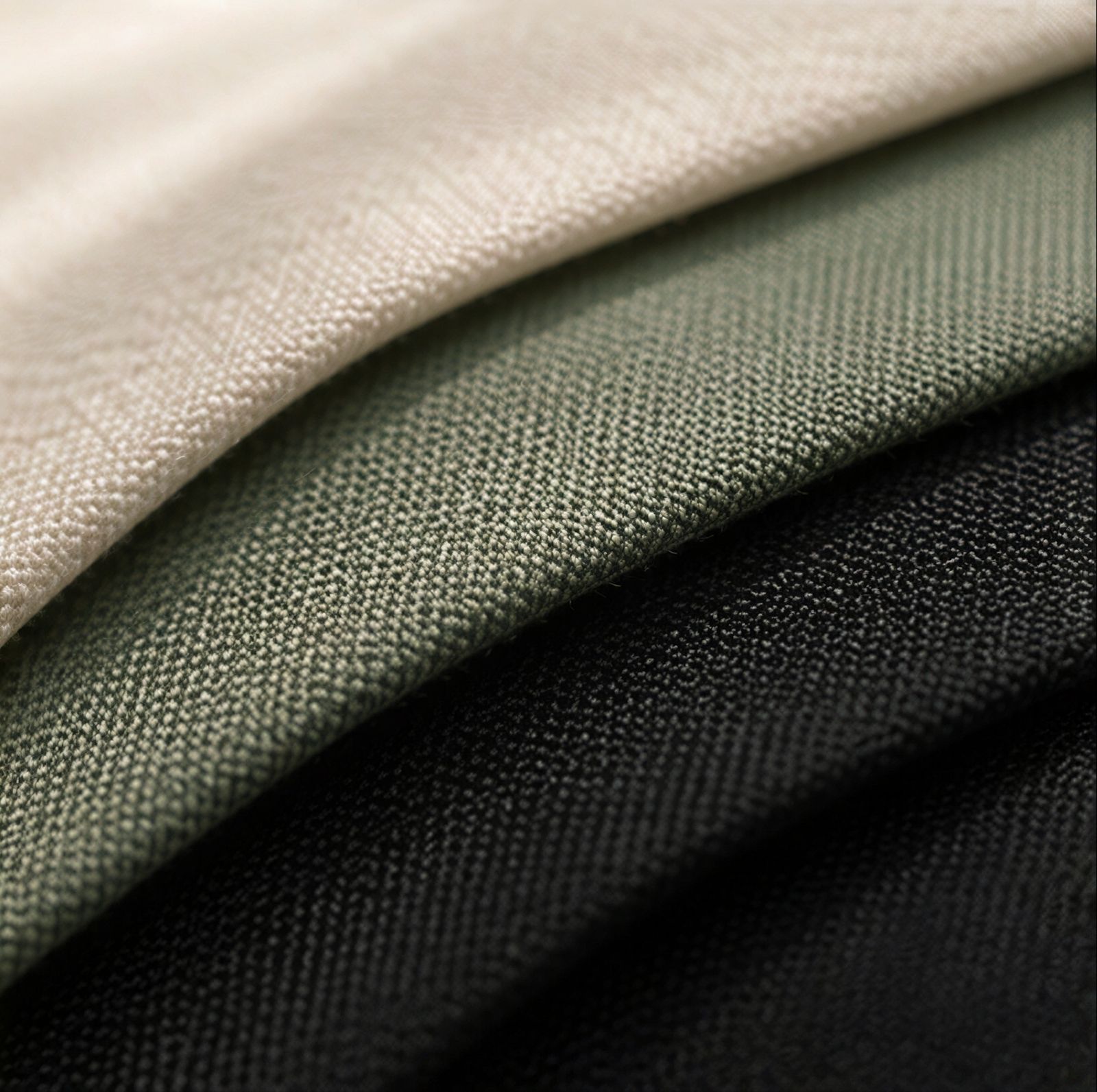 Tecidos Bella Company nas cores cru, verde e preto, dobrados em camadas